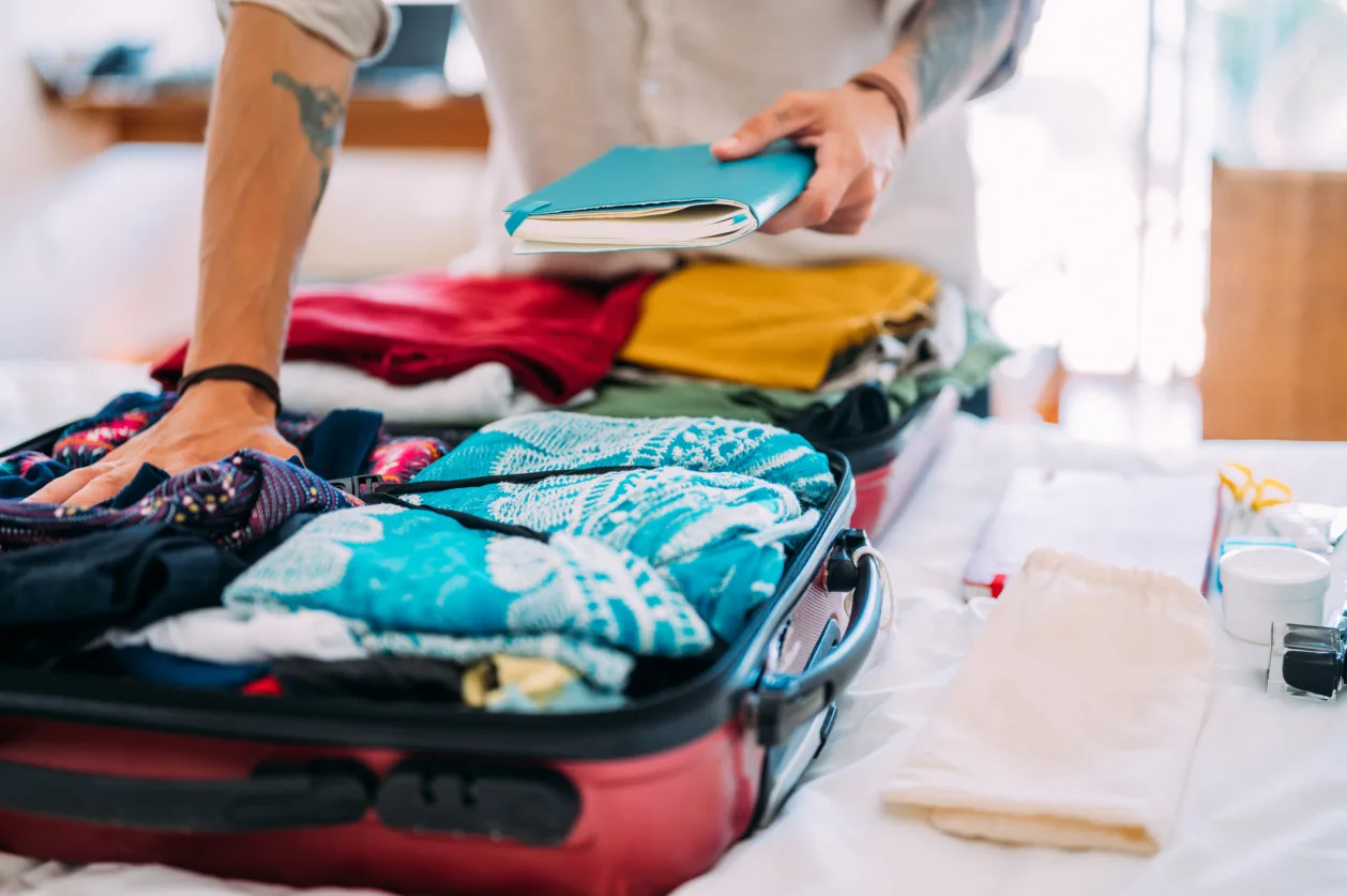 An unrecognizable man packs clothes and all the necessities for traveling with food allergies